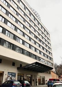 a large building with cars parked in front of it at Apartman 509 Zepterme -private host in Vrnjačka Banja