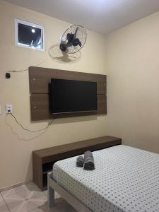 a bedroom with a bed and a flat screen tv at Residence tropical, disponível 2 quartos para alugar in Guriú