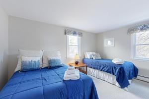 two beds in a room with blue sheets at Stone’s Throw in Kennebunkport
