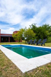 Una piscina con sillas al lado de un edificio. en Casa Quinta la PAVA GRADE, en Chascomús