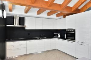 kuchnia z białymi szafkami i drewnianym sufitem w obiekcie La Pieve Apartments w mieście San Lorenzo in Banale