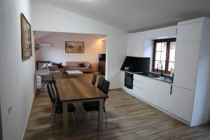a kitchen and living room with a wooden table and a dining room at Kalaja Apartment in Prizren