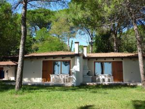 una casa con sillas blancas en el césped en Belvedere Pineta Camping Village Grado, en Grado