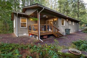 a tiny house in the woods with a large porch at Glacier Springs Cabin - Wood Stove, Hot Tub, WIFI, Sleeps 8 in Deming