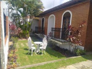 a patio with three chairs and a table in front of a house at Suite para casal in Natal