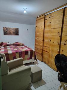 a bedroom with a bed and a couch and a chair at Suite para casal in Natal