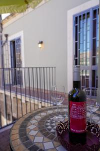 a bottle of wine sitting on a table with two glasses at Attico in centro - "La Nica" in Catania