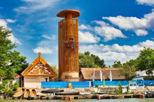 a building with a tower next to a body of water at Pensiunea Taisia in Murighiol