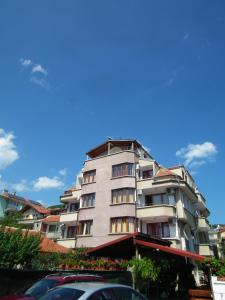 a tall building with a car parked in front of it at Guest House Olimpiya in Sveti Vlas