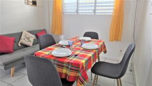 un tavolo da pranzo con sedie e un divano di Suite familiale 4 personnes chez l'habitant - Sports & aéroport à proximité a Le Lamentin