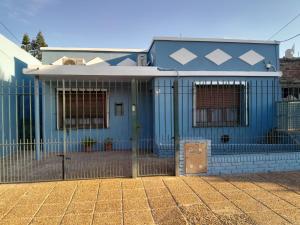 a blue house with a fence in front of it at Hospedaje Gustavo in Ezeiza