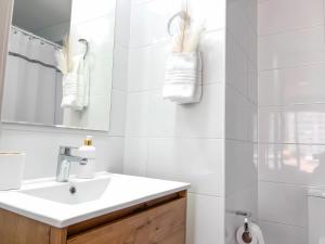 a white bathroom with a sink and a mirror at exclusive apartment with AC and parking in Santiago
