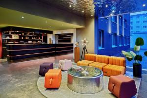 eine Lobby mit orangefarbenen und violetten Möbeln und einer Bar in der Unterkunft the Deutz, a Tribute Portfolio Hotel in Köln + 27 Fotos