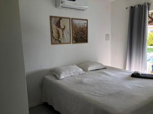 ein Schlafzimmer mit einem Bett und zwei Bildern an der Wand in der Unterkunft Praia do Flamengo 150m da praia Casa Ballalai in Salvador + 17 Fotos