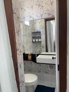 ein Badezimmer mit Toilette, Waschbecken und Spiegel in der Unterkunft Praia do Flamengo 150m da praia Casa Ballalai in Salvador