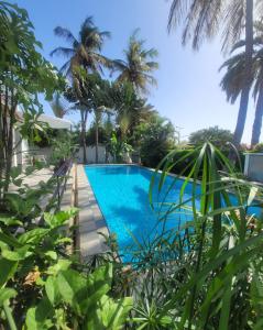 a swimming pool in front of a resort with palm trees at Maison d'hôtes villa Anna Dakar in Dakar