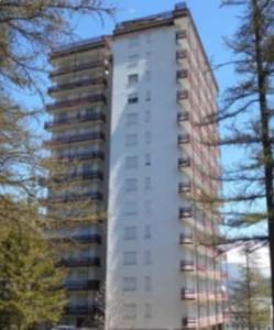 a tall white building with trees in front of it at Appartamento immerso nel verde vista panoramica in Pragelato
