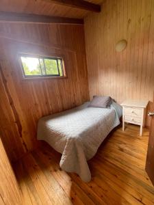 a bed in a wooden room with a window at Cabañas San Agustín in Panguipulli