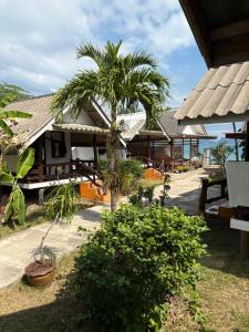 a house with a palm tree in front of it at Pyramid Bangalow in Ban Laem Sai