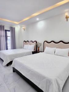 two beds in a bedroom with white walls at Kim Hotel Vincom Tây Ninh in Tây Ninh