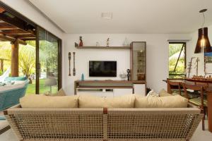 un salon avec un canapé et une télévision dans l'établissement Bangalô exclusivo no Eco Resort Carneiros, à Praia dos Carneiros