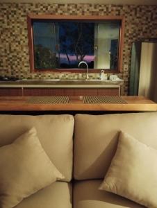a couch in a room with a sink and a window at Villa Mantiqueira - Studio I - Com lareira e área verde in Campos do Jordão