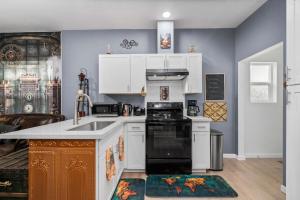 a kitchen with white cabinets and a black appliance at Steampunk Haven in the Heart of Tacoma! in Tacoma +17 photos