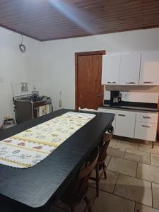 a kitchen with a black table and a kitchen with white cabinets at casa aluguel in Pântano Grande