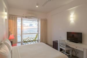 a hotel room with a bed and a desk with a view at Coral Rock by Bansei in Hikkaduwa