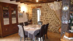 comedor con mesa, sillas y pared de piedra en Chambres d'hôtes Le Bas Rassinoux en Saint-Ouen-des-Alleux