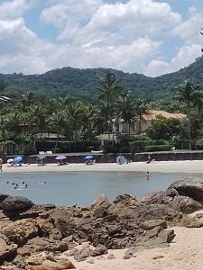 ein Strand mit Palmen und Menschen im Wasser in der Unterkunft CASA SETE ENSEADA AR COND Suíte E ESTACIONAMENTO GRÁTIS e uma ótima localização na enseada in Guarujá