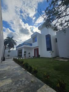 une maison blanche avec une porte rouge et une cour dans l'établissement VillaGuerra-Piscina-Billar-BBQ-WiFi-Cozy-3Br-5Bds-7Pax, à Guerra