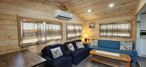 un salon avec un canapé bleu et une table dans l'établissement Trent River Cottages, à Hastings