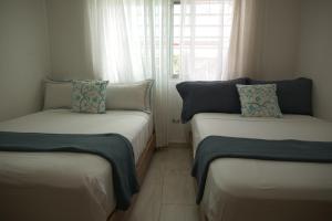 deux lits jumeaux dans une chambre avec fenêtre dans l'établissement VillaGuerra-Piscina-Billar-BBQ-WiFi-Cozy-3Br-5Bds-7Pax, à Guerra