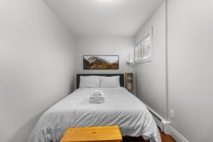 een slaapkamer met een wit bed en een houten tafel bij Forest House 1 Bdrm Qv Lake View Parking in St. John's