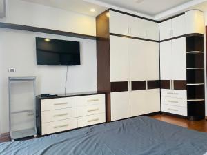 a bedroom with white cabinets and a tv on the wall at Laca Home in Hanoi