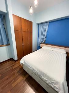 a bedroom with a bed and a blue wall at Hock Lee Hotel Residences - Anna 温馨公寓式的住宅 in Kuching