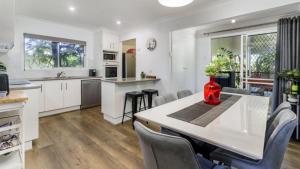 a kitchen with white cabinets and a table with chairs at Family Holiday Perfection in Bellara