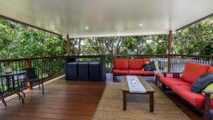 a screened in porch with red couches and a table at Family Holiday Perfection in Bellara