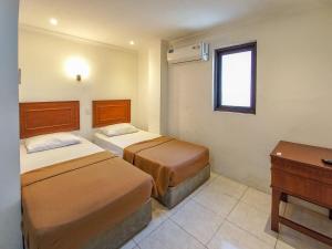 a hotel room with two beds and a desk at D Hans Hotel Syariah RedPartner near Wisata Religi Sunan Ampel Surabaya in Surabaya