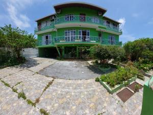 a green house with a large yard in front of it at Pousada Altos dos Ingleses II in Florianópolis