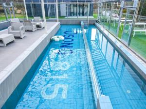 a swimming pool in a building with chairs at Geoje Osong 815 pension in Geoje