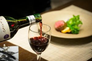 a bottle of red wine being poured into a glass at Hotel Edel Warme in Furano