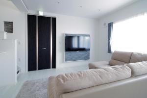 Una sala de estar con un sofá y un televisor de pantalla plana. en Mist, en Sapporo