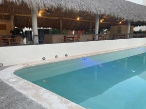 a swimming pool at a resort with a thatch roof at Beautiful and comfortable apartment in Bucerías