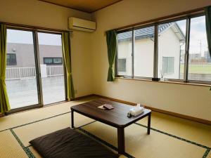 un soggiorno con tavolo e 2 finestre di Nest Kisarazu a Kisarazu