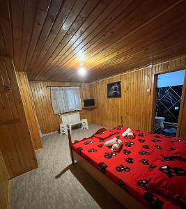 a bedroom with a red bed in a wooden room at Casa Roxana in Predeal