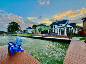 two blue chairs sitting on a wooden dock next to a house at Lakefront Oasis in Humble