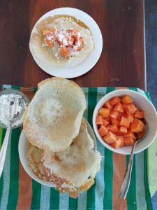 a table with two plates of food and a bowl of fruit at Coconut Grove - Midigama in Midigama East