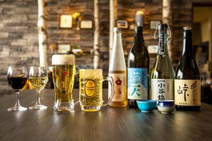 a group of bottles of wine and glasses on a table at Hotel Hakuba Berghaus in Otari